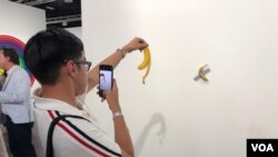 Luis Lu, un amante del arte en Nueva York, se fotografía con la banana pegada a la pared en Art Basel 2019 (Foto: Antoni Belchi)