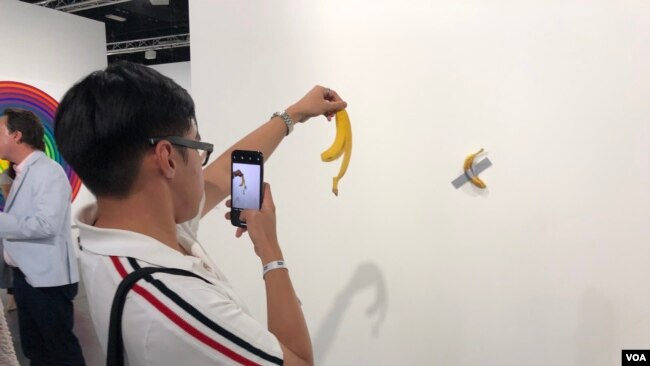 Luis Lu, un amante del arte en Nueva York, se fotografía con la banana pegada a la pared en Art Basel 2019 (Foto: Antoni Belchi)