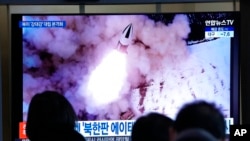 FILE - People watch a TV showing a file image of North Korea's missile launch shown during a news program at the Seoul Railway Station in Seoul, South Korea, Jan. 20, 2022.