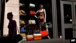In this April 10, 2013 photo, a woman walks past a retail store's window display in Baltimore.