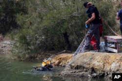 A diver enters a lake to search for female bodies near the village of Xiliatos outside of Nicosia, Cyprus, April 26, 2019. Cyprus police are intensifying a search for the remains of more victims at locations.