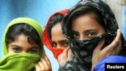 FILE - Young girls in Bangladesh cover their faces with clothes, apparently trying to hide their age, March 5, 2000.