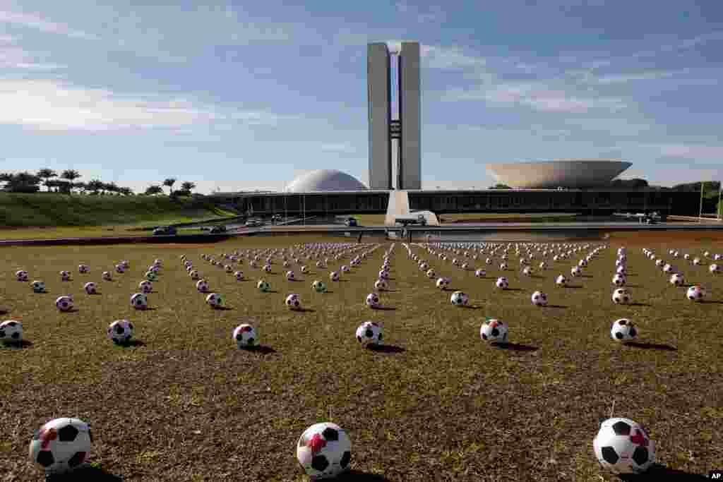 Soccer balls representing the Brazilian lawmakers sit in rows in front of Congress as a protest against spending on the Confederations Cup soccer tournament in Brasilia.