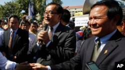 Opposition leader of Cambodia National Rescue Party Sam Rainsy, center, delivers a speech next to his Deputy President Kem Sokha, right, during a gathering to mark Human Rights Day, in front of National Assembly, in Phnom Penh, Cambodia, Wednesday, Dec. 1