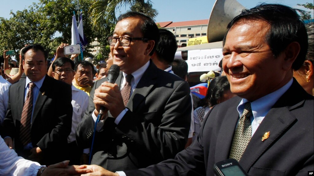 Opposition leader of Cambodia National Rescue Party Sam Rainsy, center, delivers a speech next to his Deputy President Kem Sokha, right, during a gathering to mark Human Rights Day, in front of National Assembly, in Phnom Penh, Cambodia, Wednesday, Dec. 10, 2014. (AP Photo/Heng Sinith