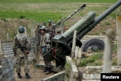 Ethnic Armenian soldiers stand next to a cannon at artillery positions near the Nagorno-Karabakh's town of Martuni, April 7, 2016.