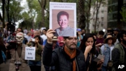 Seorang pria mengangkat foto wartawan Meksiko, Miroslava Breach, yang ditembak mati di negara bagian Chihuahua hari Kamis, selama pawai di Mexico City, 25 Maret 2017 (foto: AP Photo/Eduardo Verdugo)