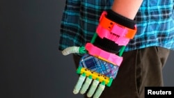 Prosthetic limbs have come a long way. Here a 12-year-old boy shows off his new, colorful, 3-D printed prosthetic hand at the new MakerBot store in Boston, Massachusetts. (Nov. 2013)