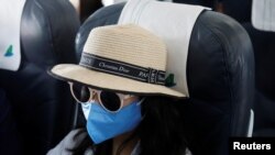 A woman wears a protective mask onboard during a flight of Bamboo Airways from Da Nang to Hanoi, Vietnam March 7, 2020. REUTERS/Kham