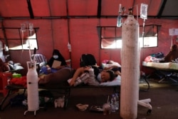 Seorang pasien COVID-19 terbaring di atas velbed di tenda sementara di luar ruang gawat darurat rumah sakit pemerintah di Bekasi, 25 Juni 2021. (Foto: REUTERS/Willy Kurniawan)