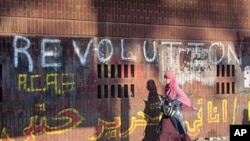 An Egyptian girl walks under slogans supporting the protest at Tahrir Square, the focal point of the Egyptian uprising where protesters have been demanding a faster pace of reforms, in Cairo, Egypt, July 18, 2011