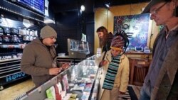 FILE - Cannabis consultant Juan Aguilar, left, assists customers Bill, right, and Nize Nylen and their son Russell shop for edible marijuana products in the Herban Legends pot shop, Thursday, Jan. 4, 2018, in Seattle. (AP Photo/Elaine Thompson)