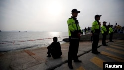 Anggota keluarga penumpang kapal Korea Selatan yang tenggelam menapat laut dari pelabuhan tempat para keluarga penumpang berkumpul di Jindo (20/4). (Reuters/Kim Hong-Ji)