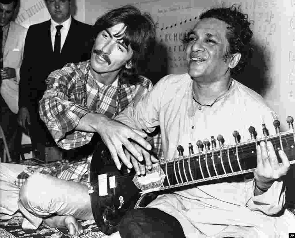 In this August 3, 1967 file photo, George Harrison, of the Beatles, left, sits with Ravi Shankar in Los Angeles, California as Harrison explains to newsmen that Shankar is teaching him to play the sitar.