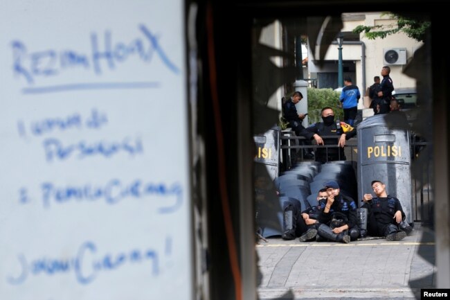 Mobile brigade (Brimob) police officers take a rest near a damaged police station after riots following the announcement of last month's presidential election results outside the Election Supervisory Agency (Bawaslu) headquarters in Jakarta, Indonesia, May 23, 2019.