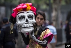 A woman walks before her performance in the Day of the Dead parade on Reforma avenue in Mexico City, Oct. 27, 2018.