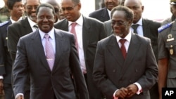 Kenya's PM Raila Odinga (l) walks with Gilbert Ake, named Prime Minister in the cabinet of Ivory Coast's incumbent leader Laurent Gbagbo, after arriving at the Felix Houphouet Boigny international airport in Abidjan, 03 Jan 2011.