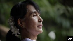 Burma's pro-democracy leader Aung San Suu Kyi looks on from behind the gates of the National League for Democracy (NLD) office as supporters and reporters gather, in Yangon, April 2, 2012.