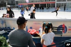 A girl in a short-sleeved shirt watches skaters in New York's Bryant Park, Feb. 24, 2017. Temperatures reached 68 degrees by noon, according to the National Weather Service.