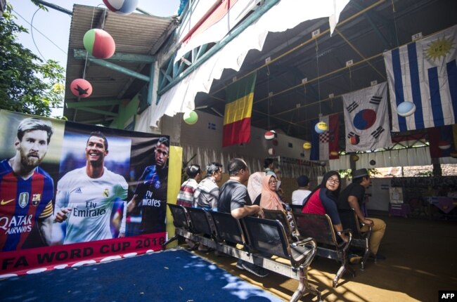 Para pemilih menunggu giliran memberikan suara dalam pilkada di sebuah TPS bertema Piala Dunia di Surabaya, 27 Juni 2018. (Foto: AFP)