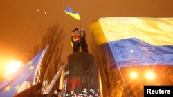 People climb up to the top of a pedestal after a statue of Soviet state founder Vladimir Lenin was toppled by protesters during a rally organized by supporters of EU integration in Kyiv, December 8, 2013.