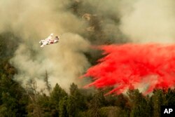 An air tanker drops retardant while fighting to stop the Ferguson Fire from reaching homes in the Darrah community of unincorporated Mariposa Count, Calif., July 25, 2018.