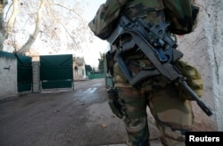 FILE - An armed French soldier secures the access to a Jewish school in France, Jan, 11, 2016, after a teenager armed with a machete and a knife, who said he acted in the name of the Islamic State, wounded a teacher before being arrested.