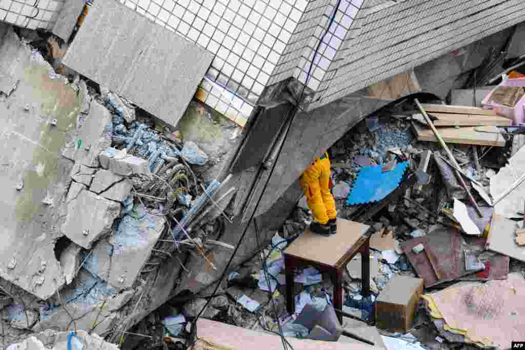 A rescue worker clears debris to make way for the recovery of the dead bodies of a Hong Kong Canadian couple from the Yun Tsui building, which is leaning at a precarious angle, in the Taiwanese city of Hualien on February 9, 2018, after the city was hit by a 6.4-magnitude quake late on February 6.