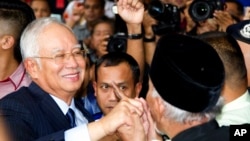 Former Prime Minister Najib Razak, left, shakes hands with his supporters as he leaves Kuala Lumpur High Court after a court hearing in Kuala Lumpur, Malaysia, Sept. 20, 2018. 