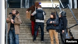 French police check a pedestrian as they secure the area after a man was shot dead at a police station in the 18th district in Paris, France January 7, 2016. 