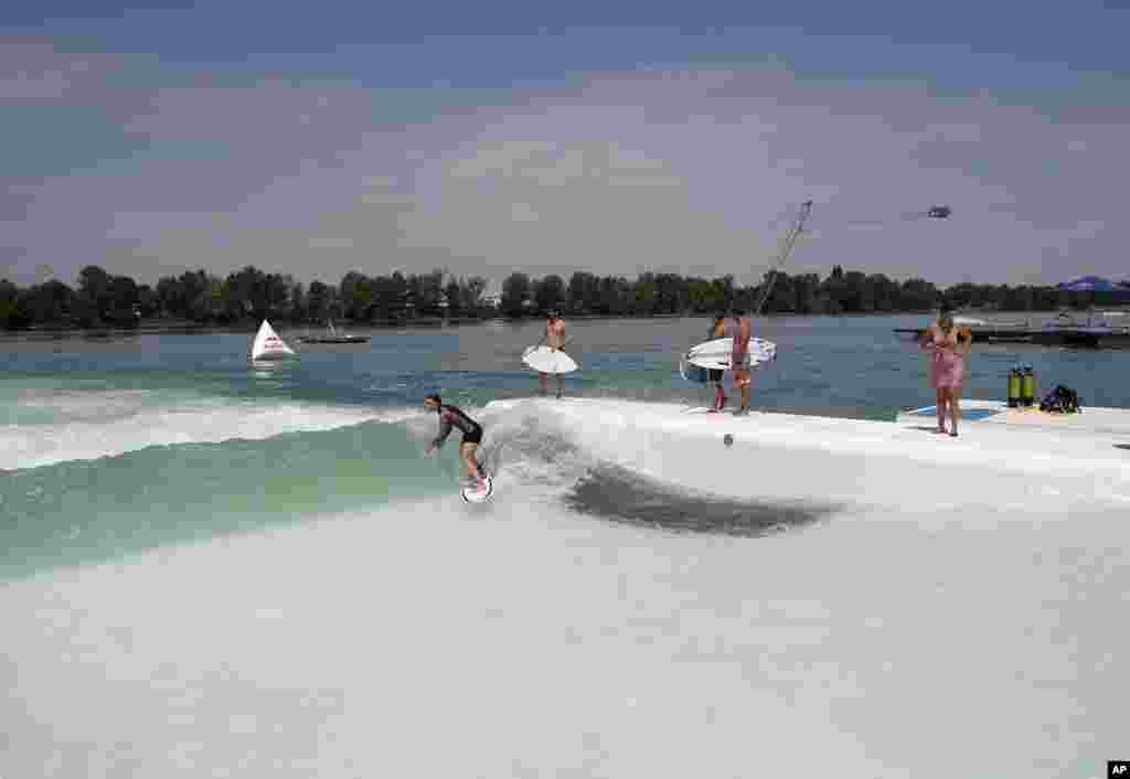 گروهی از موج سواران در هوای گرم تابستان در دریاچه ای در میلان، تن به آب زده اند.&nbsp;