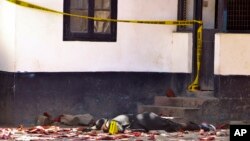 One of the bodies of three women who were shot dead by police lies outside the central police station in the coastal city of Mombasa, Kenya Sunday, Sept. 11, 2016. The three women were killed by police after they attacked the police station using petrol bombs and knives, a police official. 