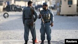 Afghan policemen keep watch at the site of an attack after an overnight battle outside a base in Kabul, Afghanistan, Aug. 8, 2015. 