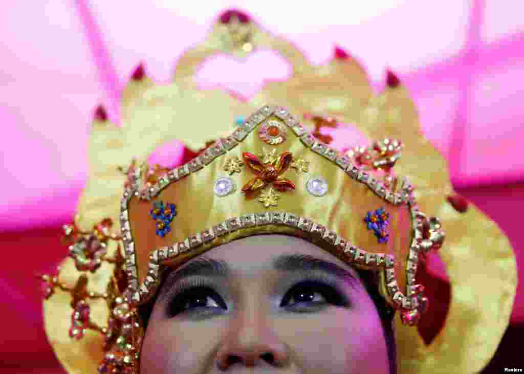 A dancer waits backstage at a street festival to celebrate Brunei&#39;s upcoming royal wedding in Bandar Seri Begawan. The royal wedding ceremony of Prince Abdul Malik and his bride Dayangku Rabiatul Adawiyah Pengiran Haji Bolkiah will be held at the Nurul Iman Palace in Brunei&#39;s capital on Sunday.