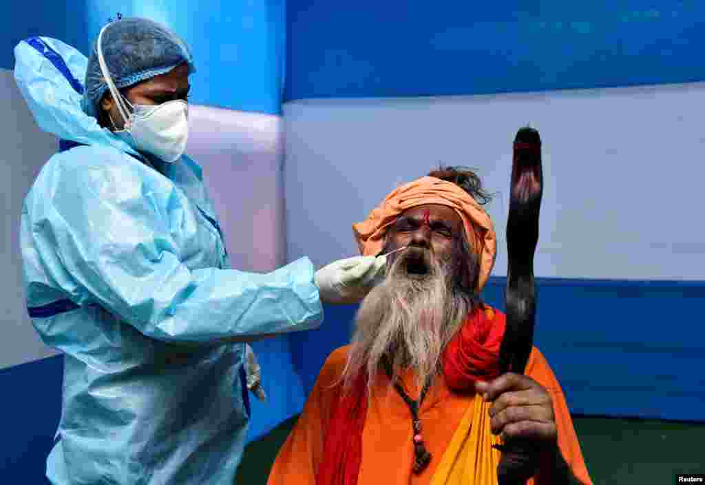 A Sadhu, or Hindu holy man, reacts as a health care worker collects a swab sample for a COVID-19 test at a base camp where pilgrims gather before heading for an annual trip to Sagar Island for the Makar Sankranti festival, in Kolkata, India.