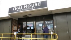 Men wait outside of the Thai House restaurant for their order since a new social distancing measure that only one can get in to order at that time Gaithersburg, MD, U.S., March 29, 2020.