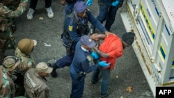 South African police officers, backed by soldiers, arrest illegal immigrants and foreign nationals during a raid in Johannesburg in the early morning hours of May 8, 2015.