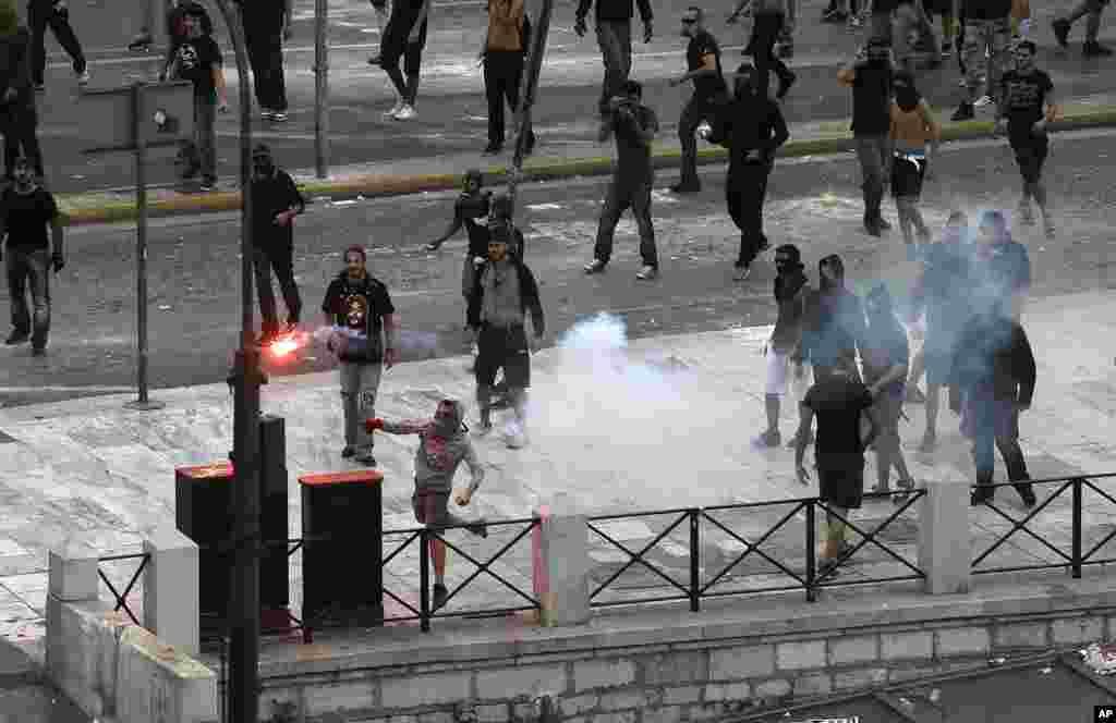A protester throws a flare towards riot police during clashes during a protest in Athens, Greece, October 9, 2012.