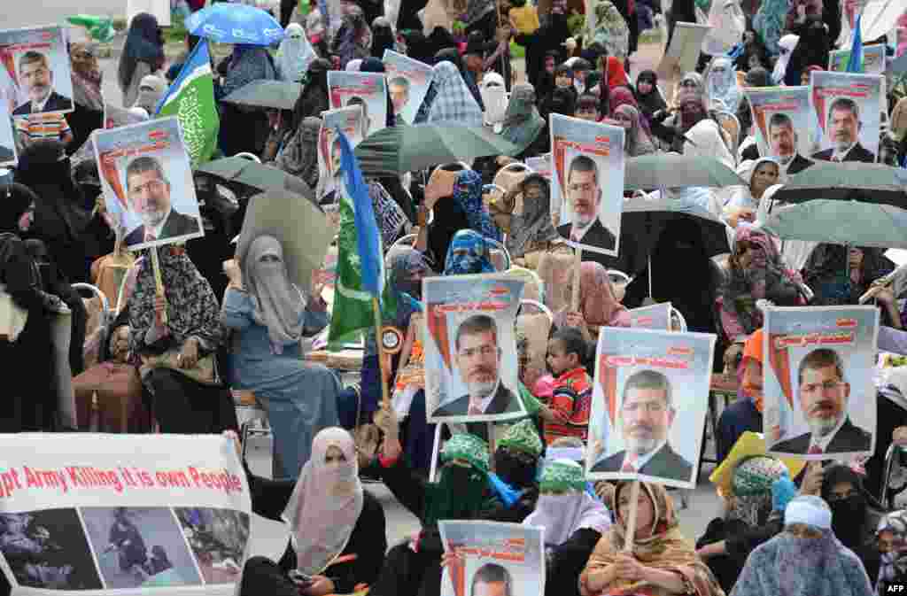 Aktivis-aktivis perempuan dari partai politik Jamaat-e-Islami (JI) di Pakistan memegang foto presiden Mesir terguling Mohamed Morsi dalam demonstrasi mendukung Morsi di Islamabad (18/8). (AFP/Farooq Naeem)