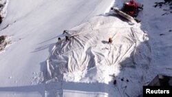 Employees of Titlis Bergbahnen cable car operator place blankets on parts of the glacier to protect it against melting on Mount Titlis near the Alpine resort of Engelberg, Switzerland July 2, 2021. (REUTERS/Arnd Wiegmann)