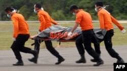 Members of an Indonesian search and rescue team carry a dead body with a stretcher during the recovery of victims who were onboard the crashed AirAsia flight QZ8501 in Pangkalan Bun on December 31, 2014. Stormy weather forced Indonesian rescuers on Decemb
