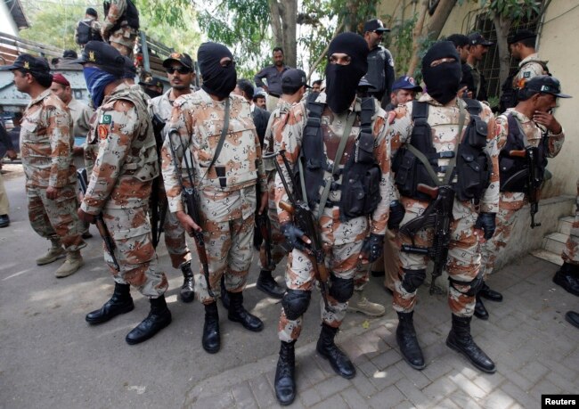 Paramilitary soldiers stand guard, as they present men (unseen), who were detained during Wednesday's raid on the Muttahida Qaumi Movement political party headquarters, before an anti-terrorism court in Karachi, March 13, 2015.