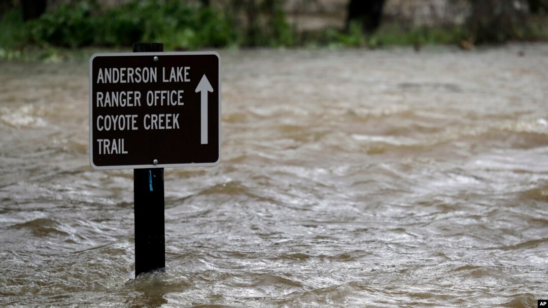 FILE - A sign is submerged in the water from Coyote Creek, Feb. 21, 2017, in Morgan Hill, Calif. Rains have saturated once-drought stricken California but have created chaos for residents hit hard by the storms.