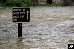FILE - A sign is submerged in the water from Coyote Creek, Feb. 21, 2017, in Morgan Hill, Calif. Rains have saturated once-drought stricken California but have created chaos for residents hit hard by the storms.