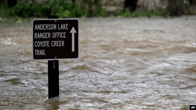 FILE - A sign is submerged in the water from Coyote Creek, Feb. 21, 2017, in Morgan Hill, Calif. Rains have saturated once-drought stricken California but have created chaos for residents hit hard by the storms.