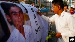 A Cambodian worker gives a signature on a poster of Chea Vichea during the 11th anniversary of the assassination of Chea Vichea, former head of Cambodia's Free Trade Union of Workers, in Phnom Penh, Cambodia, Thursday, Jan. 22, 2015. (AP Photo/Heng Sinith)