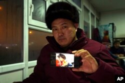 In this Dec. 9, 2018, photo, Orynbek Koksebek, a former detainee in a Chinese internment camp, holds up a phone showing a state television report about what Beijing calls "vocational training centers" for a photo in a restaurant in Almaty, Kazakhstan.