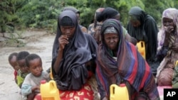 Somali women and children from southern Somalia wait in the rain with some basic rations at a displaced camp in Mogadishu, Somalia, July 15, 2011