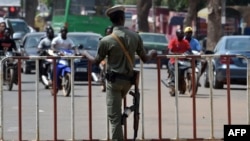 L'officier de police burkinabé monte la garde devant une porte lors de la dernière étape du Tour du Faso 2018, à Ouagadougou, le 4 novembre 2018.