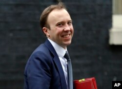 FILE - In this Jan. 9, 2018 file photo, Matt Hancock smiles after leaving a Cabinet meeting in London.